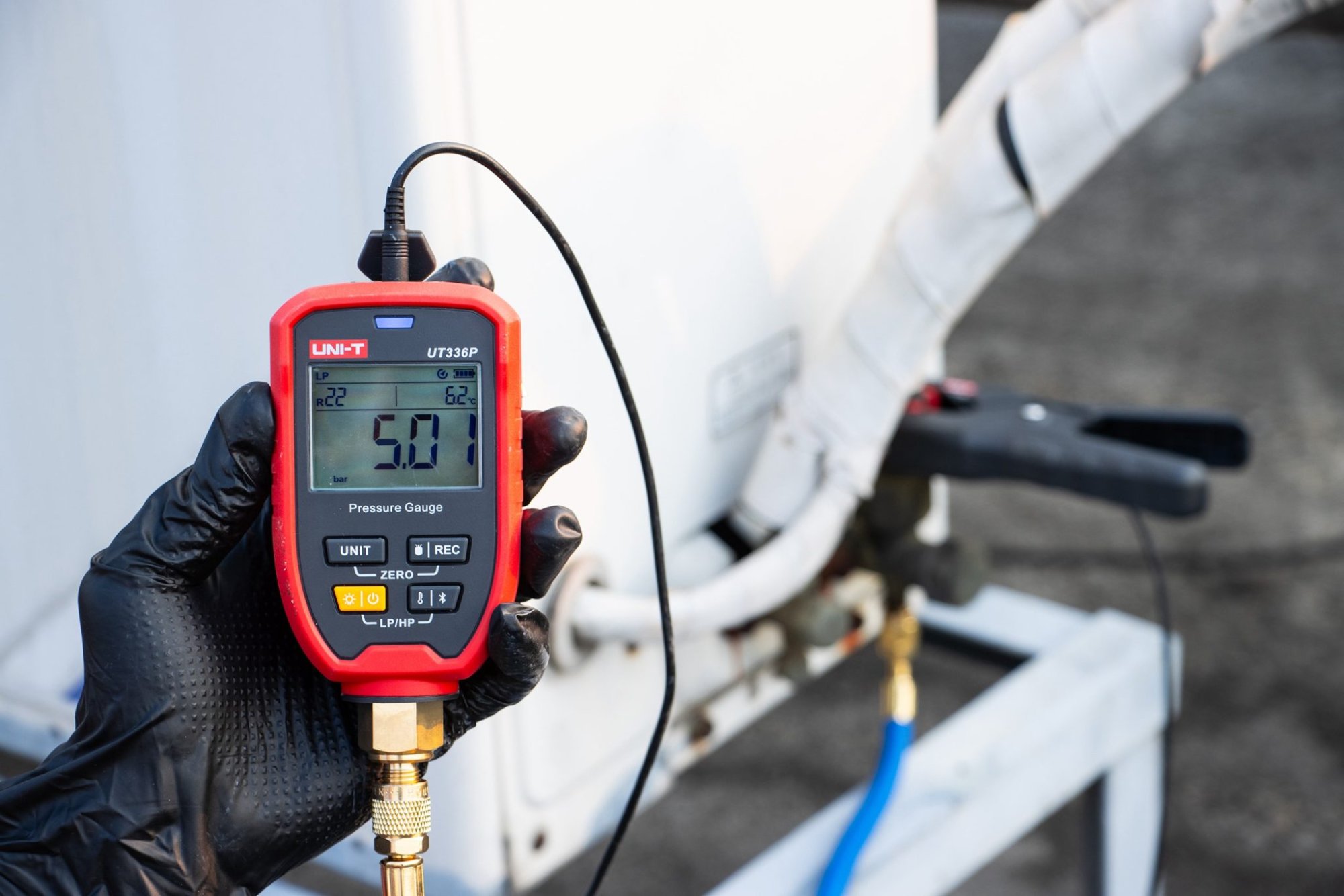 Nahaufnahme: UNI-T UT336P KIT Druckmessgerät in der Hand eines Technikers an einer Klimaanlage.