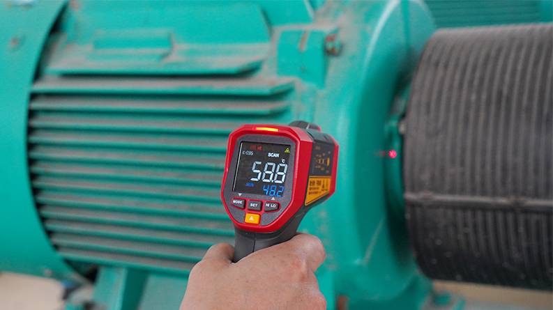 Hand hält das UNI-T UT305S Infrarot-Thermometer zur Temperaturmessung an einem Industriemotor.