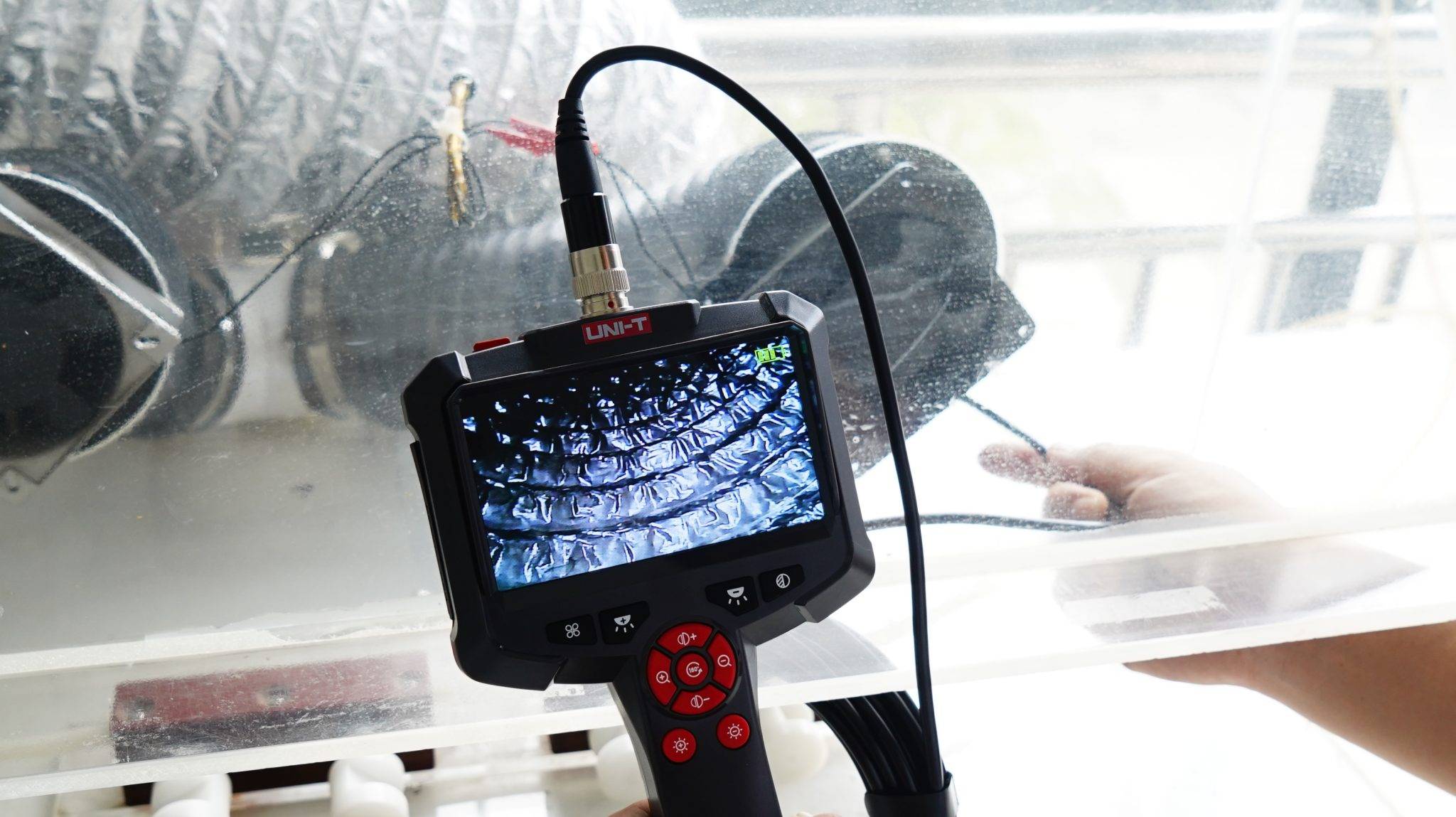 UNI-T UT665P Endoskop wird zur Untersuchung eines glänzenden, metallischen Rohres verwendet.
