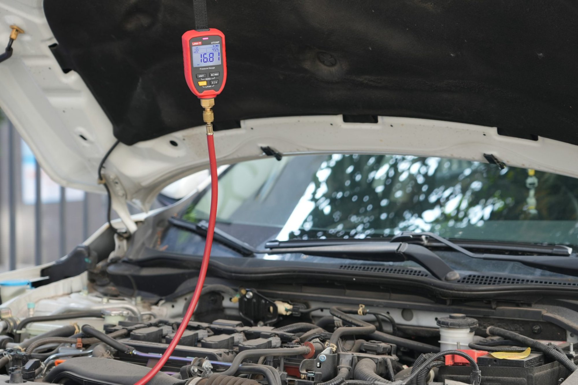 UNI-T UT336P KIT Druckmessgerät im Einsatz an einer Kfz-Klimaanlage unter der Motorhaube aufgehängt.